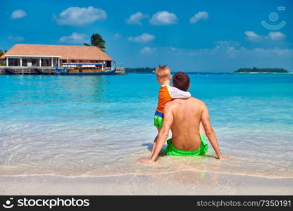 Three year old toddler boy on beach with father. Summer family vacation at Maldives.