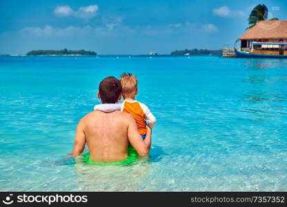 Three year old toddler boy on beach with father. Summer family vacation at Maldives.