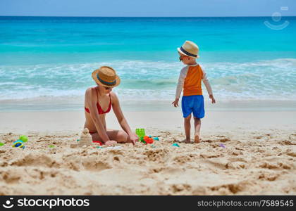 Three year old toddler boy on beach with mother. Summer family vacation at at Seychelles, Mahe.