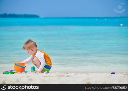 Three year old toddler boy playing with beach toys on beach.  Summer family vacation at Maldives.