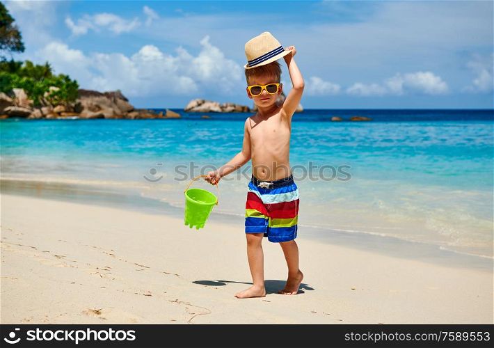 Three year old toddler boy playing with beach toys on beach. Summer family vacation at Seychelles, Mahe.