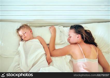 Three year old toddler boy sleeping on pillow with mother