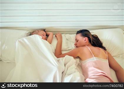 Three year old toddler boy sleeping on pillow with mother 