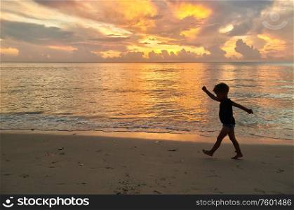 Three year old toddler boy walking on beach at sunset. Summer family vacation at Seychelles, Mahe.