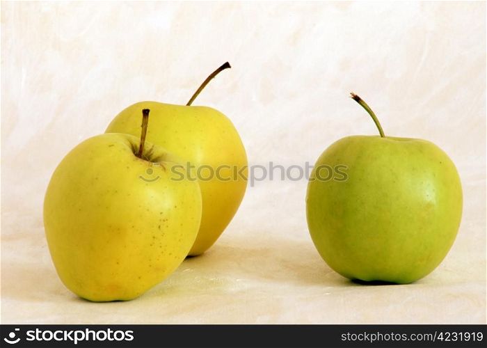Three yellow apples on painted background
