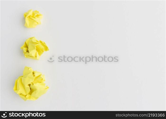 three yellow crumpled paper ball different sizes against white background