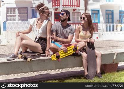 Three young active friends enjoying a summer sunny day skateboarding near typical Costa Nova houses in Aveiro - Portugal.