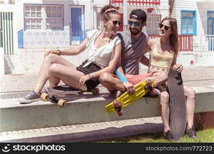 Three young active friends enjoying a summer sunny day skateboarding near typical Costa Nova houses in Aveiro - Portugal.