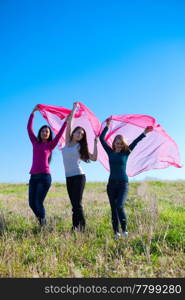 three young beautiful woman standing with tissue into the field against the sky