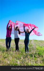 three young beautiful woman standing with tissue into the field against the sky