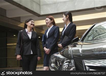Three young businesswomen meeting and talking in parking garage