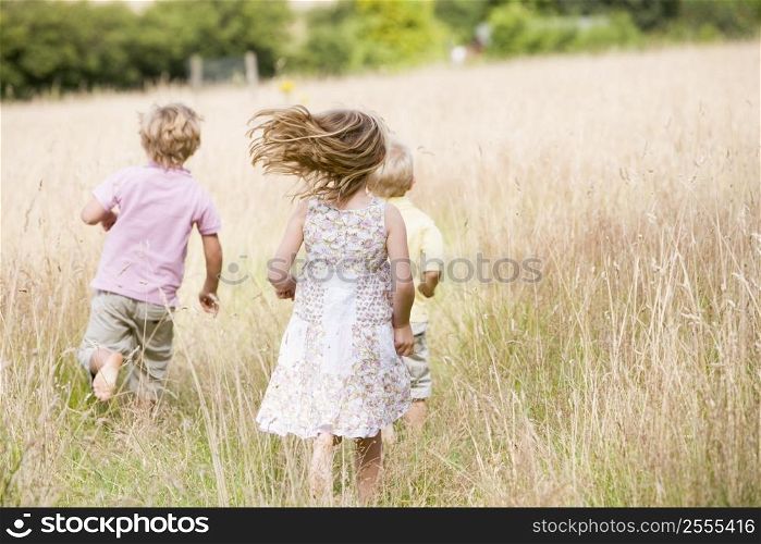 Three young children running outdoors