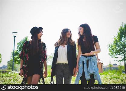 Three young female friends chatting whilst strolling in park