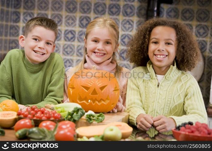 Three young friends on Halloween with jack o lantern and food smiling