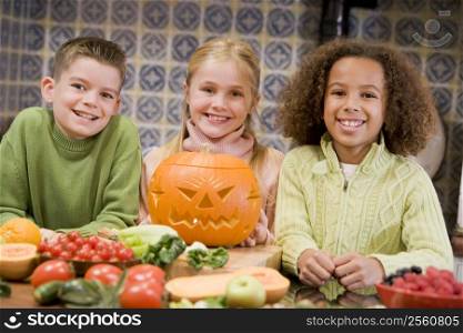 Three young friends on Halloween with jack o lantern and food smiling