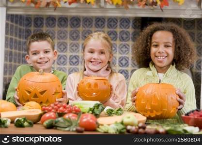 Three young friends on Halloween with jack o lanterns and food smiling