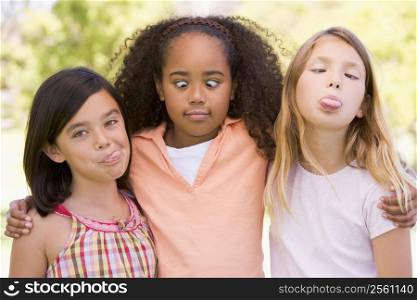 Three young girl friends outdoors making funny faces