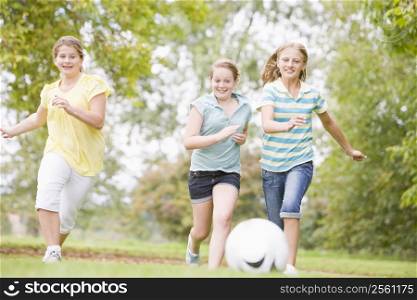 Three young girl friends playing soccer