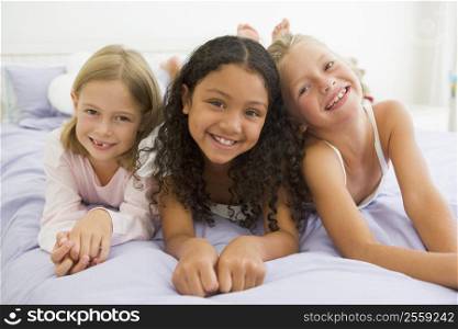 Three Young Girls Lying On A Bed In Their Pajamas