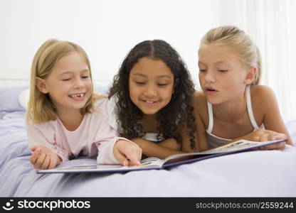 Three Young Girls Lying On A Bed In Their Pajamas