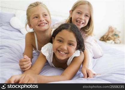 Three Young Girls Lying On Top Of Each Other In Their Pajamas