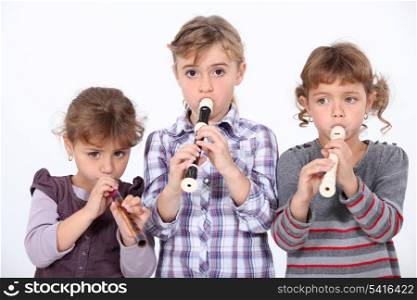 Three young girls playing the recorder