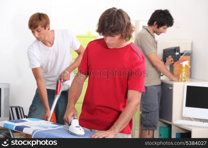 Three young male house-mates cleaning