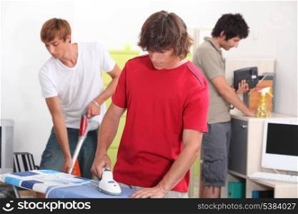 Three young male house-mates cleaning