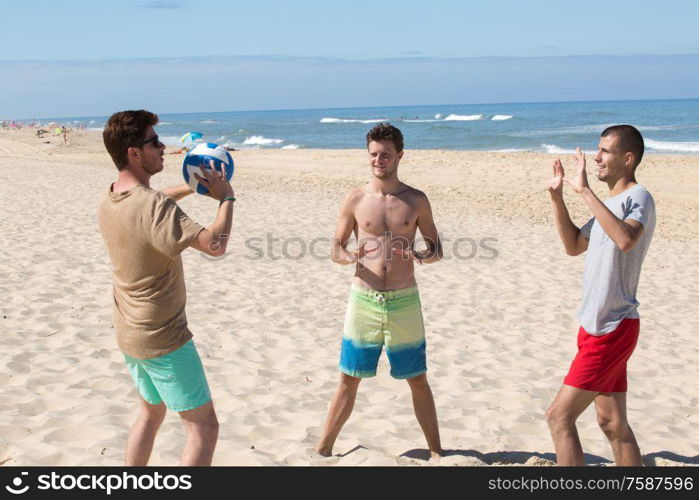 three young men having fun on the beach playing volleyball