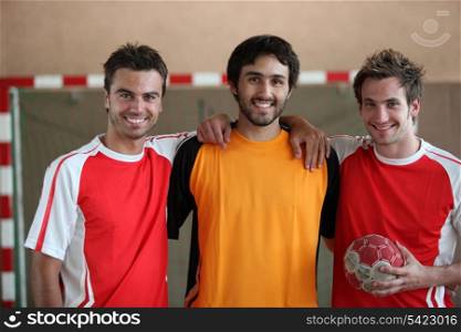 Three young men indoors with hand ball