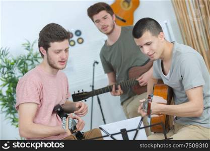 three young men playing guitars and singing