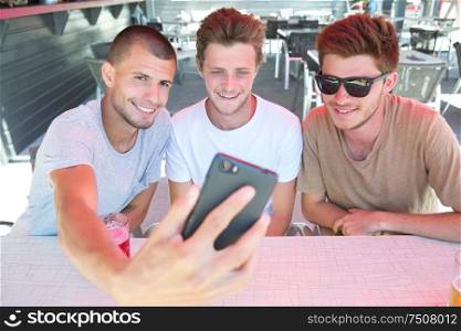 three young men taking selfie while sitting in pub