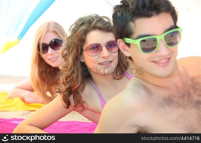 Three young men wearing sunglasses on the beach