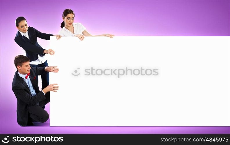 Three young people holding banner. Image of three young people holding blank banner against purple background. Place for text
