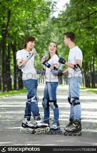Three young people on rollers drink water