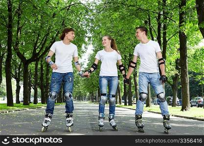 Three young people riding on roller skates holding hands