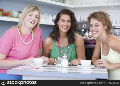 Three young woman sitting at a table and drinking tea