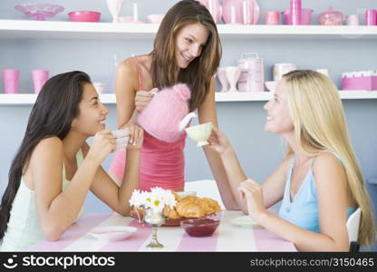 Three young woman sitting at a table having tea and a snack