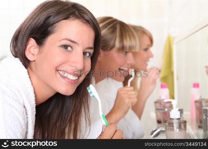 Three young women brushing their teeth