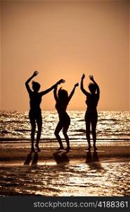Three Young Women Dancing On Beach At Sunset