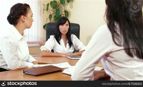 Three Young Women Discussing Business Issues in Office, Focus on Background