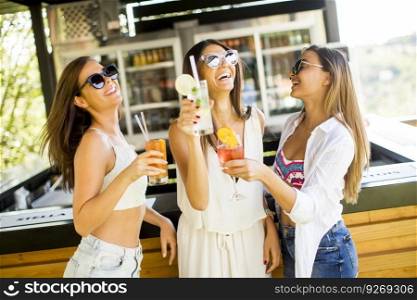 Three young women drinking coctais and having fun in beach bar