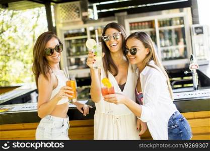 Three young women drinking coctais and having fun in beach bar