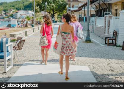 Three young women girl friends tourist walking in summer dress sunny day in spring autumn in Mediterranean town tourist destination looking restaurant accommodation rooms hotel market