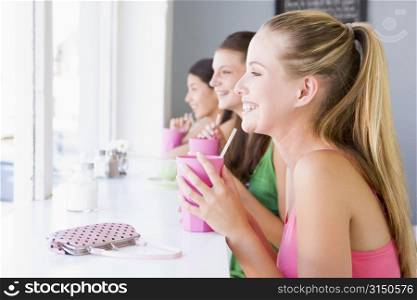 Three young women having a cold drink in a cafeteria
