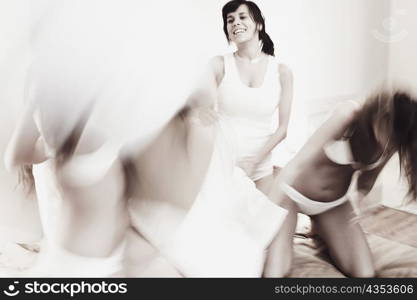 Three young women having a pillow fight on the bed