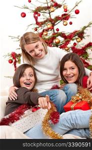 Three young women having fun on Christmas in front of tree