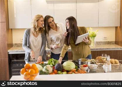 Three young women in the modern kitchen with tablet