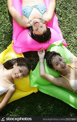 Three young women lying on pool raft