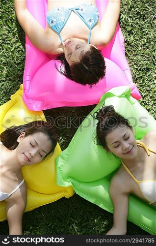 Three young women lying on pool raft